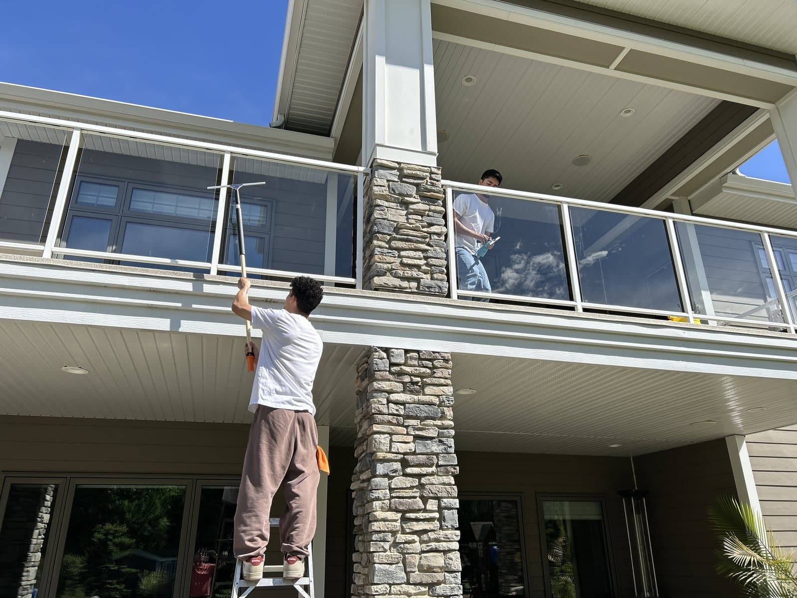 MTZ crew cleaning exterior windows and glass railings on a house